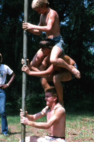 File:Boys getting onto each other's shoulders for greased pole game in White Springs, Florida, United States (1982).png